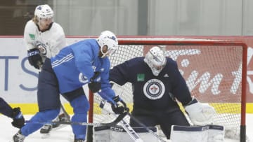 Jul 14, 2020; Winnipeg, Manitoba, USA; Winnipeg Jets goaltender Connor Hellebuyck (37) blocks a shot from Winnipeg Jets center Adam Lowry (17) during a NHL workout at Bell MTS Iceplex. Mandatory Credit: James Carey Lauder-USA TODAY Sports