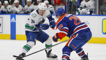 Oct 12, 2022; Edmonton, Alberta, CAN; Vancouver Canucks forward Andrei Kuzmenko (96) tries to move the puck past Edmonton Oilers defensemen Ryan Murray (28) during the second period at Rogers Place. Mandatory Credit: Perry Nelson-USA TODAY Sports