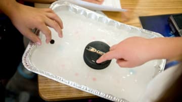 ORANGE, CA - FEBRUARY 21: Students in Jim Violette's class test the friction of a hockey puck on their home-made ice rink during a 4th Grade science project at Salem Lutheran School in Orange Friday. Mr. Violette, along with fellow 4th Grade teacher Susie Woods, utilize the Anaheim Ducks' First Flight Field Trip and SCORE program.///ADDITIONAL INFO:Family.Cover.0304.kjs --- Photo by KEVIN SULLIVAN / Orange County Register -- 2/21/14For the OC Family cover for March 4, we are doing a story on the Anaheim Ducks' First Flight Field Trip and SCORE program. The writer Jenelyn Russo has a teacher lined up at Salem Lutheran School in Orange who is participating in this program. Mr. Jim Violette uses the Ducks handbook in his class and his class has already completed one of the projects from it that the photographer can take pictures of as well.Here is a link for more information about the Ducks' program: http://www.ducksscore.com/firstflight.htmlShoot date: Friday, Feb. 21Subject: Mr. Jim Violette - fourth grade teacher at Salem Lutheran School2/21/14(Photo by Kevin Sullivan/Digital First Media/Orange County Register via Getty Images)