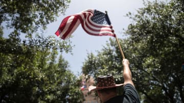 AUSTIN, TX - JUNE 30: A demonstrator waves an American flag during a rally against the Trump administration's immigration policies outside of the Texas Capitol in Austin, Texas, on June 30, 2018. Demonstrations are being held in cities across the U.S. Saturday to call for the reunification of separated families and to protest the detention of children and families seeking asylum at the border. (Photo by Tamir Kalifa/Getty Images)