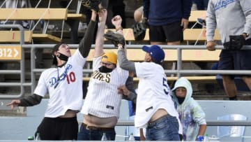 Apr 25, 2021; Los Angeles, California, USA; A San Diego Padres fan reaches up to vie for a home run hit by Los Angeles Dodgers second baseman Chris Taylor (3) between two Dodger fans during the sixth inning at Dodger Stadium. Mandatory Credit: Kelvin Kuo-USA TODAY Sports