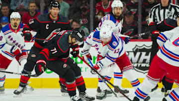 Mar 20, 2022; Raleigh, North Carolina, USA; New York Rangers left wing Alexis Lafrenière (13) and Carolina Hurricanes right wing Jesper Fast (71) battle over the loose puck during the first period at PNC Arena. Mandatory Credit: James Guillory-USA TODAY Sports