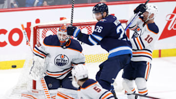 Feb 19, 2022; Winnipeg, Manitoba, CAN; Edmonton Oilers goaltender Mikko Koskinen (19) and Winnipeg Jets right wing Blake Wheeler (26) eye the puck in the third period at Canada Life Centre. Mandatory Credit: James Carey Lauder-USA TODAY Sports