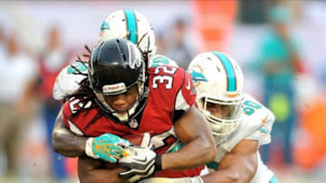 Sep 22, 2013; Miami Gardens, FL, USA; Atlanta Falcons running back Jacquizz Rodgers (center) is tackled by Miami Dolphins defensive end Olivier Vernon (right) and free safety Reshad Jones (left) during the second half at Sun Life Stadium. Mandatory Credit: Steve Mitchell-USA TODAY Sports
