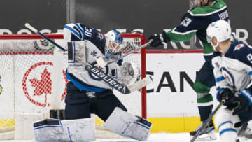 VANCOUVER, BC - FEBRUARY 19: Goalie Laurent Brossoit #30 of the Winnipeg Jets stops a redirected puck off the stick of Bo Horvat #53 of the Vancouver Canucks during NHL hockey action at Rogers Arena on February 19, 2021 in Vancouver, Canada. The Jets defeated the Canucks 2-0. (Photo by Rich Lam/Getty Images)