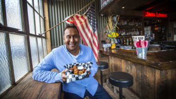 Host Ali Khan holds a plate of Fried Mormon Funeral Potatoes at the Garage on Beck in Salt Lake City, Utah as seen on Cooking Channel’s Cheap Eats, Season 2. Photo provided by Food Network
