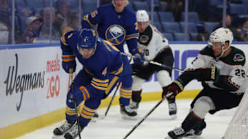 Oct 16, 2021; Buffalo, New York, USA; Buffalo Sabres defenseman Will Butcher (4) skates behind the net with the puck as Arizona Coyotes left wing Johan Larsson (22) defends during the first period at KeyBank Center. Mandatory Credit: Timothy T. Ludwig-USA TODAY Sports