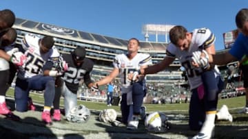 Oct 12, 2014; Oakland, CA, USA; San Diego Chargers players Darrell Stuckey (25), Philip Rivers (17) and John Phillips (83) and Oakland Raiders safety Usama Young (26) join hands in prayer after the game at O.co Coliseum. The Chargers defeated the Raiders 31-28. Mandatory Credit: Kirby Lee-USA TODAY Sports