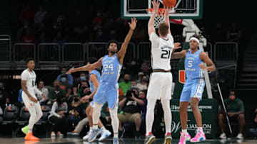 Jan 18, 2022; Coral Gables, Florida, USA; Miami Hurricanes forward Sam Waardenburg (21) attempts a three point shot over North Carolina Tar Heels guard Kerwin Walton (24) during the first half at Watsco Center. Mandatory Credit: Jasen Vinlove-USA TODAY Sports