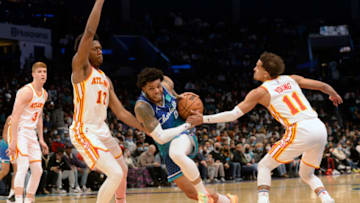 Jan 23, 2022; Charlotte, North Carolina, USA; Charlotte Hornets forward Miles Bridges (0) drives through the defense of Atlanta Hawks center Onyeka Okungwo (17) and guard Trae Young (11) during the second half at The Spectrum Center. Mandatory Credit: Sam Sharpe-USA TODAY Sports