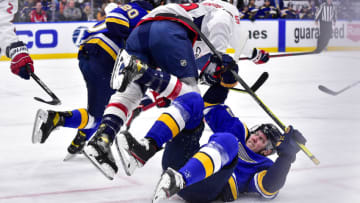 Jan 7, 2022; St. Louis, Missouri, USA; Washington Capitals center Nic Dowd (26) flips over St. Louis Blues center Oskar Sundqvist (70) after a face off during the second period at Enterprise Center. Mandatory Credit: Jeff Curry-USA TODAY Sports