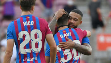 Barcelona's rookie Spanish midfielder Gavi is hugged by Barcelona's Dutch forward Memphis Depay. (Photo by LLUIS GENE/AFP via Getty Images)