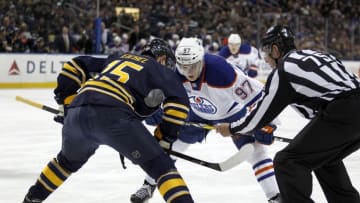 Mar 1, 2016; Buffalo, NY, USA; NHL linesman Derek Amell (75) drops the puck for a face-off between Buffalo Sabres center Jack Eichel (15) and Edmonton Oilers center Connor McDavid (97) during the first period at First Niagara Center. Mandatory Credit: Timothy T. Ludwig-USA TODAY Sports