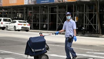 NEW YORK, NEW YORK - MAY 22: A United States Postal Service (USPS) worker wearing a protective mask and gloves pushes a cart across the street in Midtown Manhattan during the coronavirus pandemic on May 22, 2020 in New York City. COVID-19 has spread to most countries around the world, claiming over 336,000 lives and infecting over 5.1 million people. (Photo by Dia Dipasupil/Getty Images)