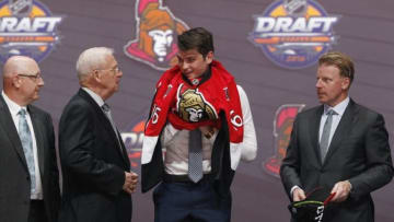 Jun 24, 2016; Buffalo, NY, USA; Logan Brown puts on a team jersey after being selected as the number eleven overall draft pick by the Ottawa Senators in the first round of the 2016 NHL Draft at the First Niagra Center. Mandatory Credit: Timothy T. Ludwig-USA TODAY Sports
