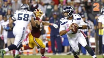 Oct 6, 2014; Landover, MD, USA; Seattle Seahawks quarterback Russell Wilson (3) prepares to throw the ball as Washington Redskins outside linebacker Ryan Kerrigan (91) chases in the third quarter at FedEx Field. The Seahawks won 27-17. Mandatory Credit: Geoff Burke-USA TODAY Sports