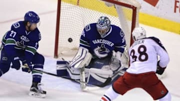 Feb 4, 2016; Vancouver, British Columbia, CAN; Columbus Blue Jackets forward Boone Jenner (38) shoots the puck against Vancouver Canucks goaltender Ryan Miller (30) and defenseman Ben Hutton (27) during the third period at Rogers Arena. The Blue Jackets won 2-1. Mandatory Credit: Anne-Marie Sorvin-USA TODAY Sports