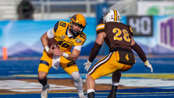 Dec 21, 2021; Boise, Idaho, USA; Kent State Golden Flashes quarterback Collin Schlee (19) runs the ball as Wyoming Cowboys linebacker Easton Gibbs (28) defends during the first half of the 2021 Famous Idaho Potato Bowl at Albertsons Stadium. Mandatory Credit: Brian Losness-USA TODAY Sports
