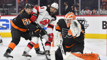 May 1, 2021; Philadelphia, Pennsylvania, USA; Philadelphia Flyers goaltender Brian Elliott (37) eyes the puck as defenseman Justin Braun (61) holds off New Jersey Devils center Nico Hischier (13) during the second period at Wells Fargo Center. Mandatory Credit: Eric Hartline-USA TODAY Sports