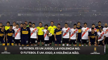 Players of Boca Juniors (blue and yellow), River Plate (red stripe) and the referees pose for pictures before the start of their all-Argentine Copa Libertadores semi-final first leg football match at the Monumental stadium in Buenos Aires, on October 1, 2019. - The banner reads "Football is a Game, Violence is Not." (Photo by Alejandro PAGNI / AFP) (Photo by ALEJANDRO PAGNI/AFP via Getty Images)
