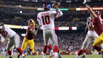 Dec 1, 2013; Landover, MD, USA; New York Giants quarterback Eli Manning (10) throws the ball as Washington Redskins outside linebacker Ryan Kerrigan (91) and Redskins nose tackle Barry Cofield (96) chase in the third quarter at FedEx Field. The Giants won 24-17. Mandatory Credit: Geoff Burke-USA TODAY Sports