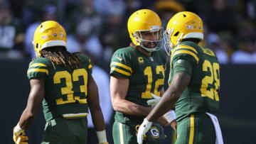GREEN BAY, WISCONSIN - OCTOBER 24: Aaron Jones #33, Aaron Rodgers #12, and AJ Dillon #28 of the Green Bay Packers meet before the game against the Washington Football Team at Lambeau Field on October 24, 2021 in Green Bay, Wisconsin. (Photo by Stacy Revere/Getty Images)