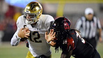 Notre Dame Fighting Irish quarterback Ian Book (12) runs the ball against Louisville Cardinals defensive back Khane Pass (30) during the second quarter at Cardinal Stadium. Mandatory Credit: Jamie Rhodes-USA TODAY Sports