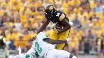 IOWA CITY, IOWA- SEPTEMBER 16: Wide receiver Brandon Smith #12 of the Iowa Hawkeyes is brought down during the second quarter by defensive back Eric Jenkins #2 and safety Khairi Muhammad #4 of the North Texas Mean Green on September 16, 2017 at Kinnick Stadium in Iowa City, Iowa. (Photo by Matthew Holst/Getty Images)