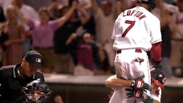 CLEVELAND, UNITED STATES: Cleveland Indians center fielder Kenny Lofton (top R) leaps into the arms of teammate Eddie Taubensee (bottom R) after scoring the game-winning run on a Jolbert Cabrera single in the 11th inning as Seattle Mariners catcher Tom Lampkin (L) holds the ball, 05 August, 2001 at Jacobs Field in Cleveland, OH. Cleveland defeated Seattle 15-14 in 11 innings. AFP PHOTO/David MAXWELL (Photo credit should read DAVID MAXWELL/AFP via Getty Images)