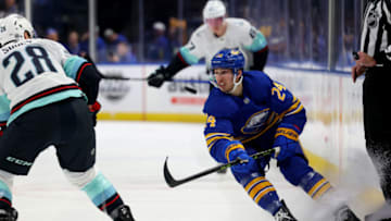 Jan 10, 2023; Buffalo, New York, USA; Buffalo Sabres center Dylan Cozens (24) flips the puck up ice as Seattle Kraken defenseman Carson Soucy (28) defends during the second period at KeyBank Center. Mandatory Credit: Timothy T. Ludwig-USA TODAY Sports