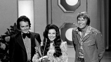 Loretta Lynn, center, accepts the Female Vocalist of the Year award at the seventh annual CMA Awards show at the Ryman Auditorium Oct. 15, 1973. Looking on are presenters Merle Haggard, left, and Glen Campbell.731015 E