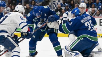 VANCOUVER, BC - DECEMBER 10: Goalie Jacob Markstrom #25 of the Vancouver Canucks scrambles to find the puck while teammate Tyler Myers #57 looks to clear before Nic Petan #61 of the Toronto Maple Leafs can get a stick on the puck during NHL action at Rogers Arena on December 10, 2019 in Vancouver, Canada. (Photo by Rich Lam/Getty Images)