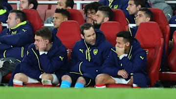 LONDON, ENGLAND - MARCH 07: Alexis Sanchez appears to smirk as he, Aaron Ramsey and Petr Cech of Arsenal watch from the bench during the UEFA Champions League Round of 16 second leg match between Arsenal FC and FC Bayern Muenchen at Emirates Stadium on March 7, 2017 in London, United Kingdom. (Photo by Catherine Ivill - AMA/Getty Images)