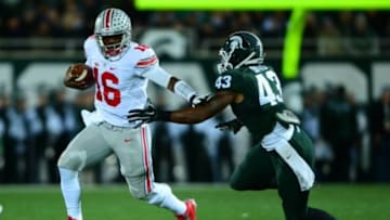 Nov 8, 2014; East Lansing, MI, USA; Ohio State Buckeyes quarterback J.T. Barrett (16) runs the ball away from Michigan State Spartans linebacker Ed Davis (43) during the first quarter at Spartan Stadium. Mandatory Credit: Andrew Weber-USA TODAY Sports
