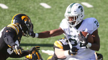 IOWA CITY, IOWA- NOVEMBER 7: Running back Elijah Collins #24 of the Michigan State Spartans fights off a tackle in the first half from defensive backs Riler Moss #33 and Jack Koerner #28 of the Iowa Hawkeyes at Kinnick Stadium on November 7, 2020 in Iowa City, Iowa. (Photo by Matthew Holst/Getty Images)