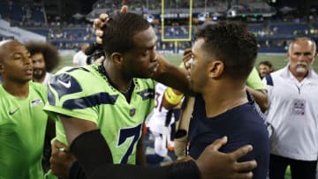 SEATTLE, WASHINGTON - SEPTEMBER 12: Geno Smith #7 of the Seattle Seahawks and Russell Wilson #3 of the Denver Broncos speak after the Seahawks defeated the Broncos 17-16 at Lumen Field on September 12, 2022 in Seattle, Washington. (Photo by Steph Chambers/Getty Images)