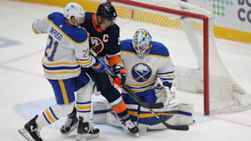 Mar 6, 2021; Uniondale, New York, USA; Buffalo Sabres goalie Carter Hutton (40) makes a save in front of New York Islanders center Anders Lee (27) and Sabres right wing Kyle Okposo (21) during the first period at Nassau Veterans Memorial Coliseum. Mandatory Credit: Brad Penner-USA TODAY Sports