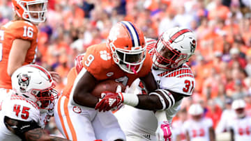 CLEMSON, SC - OCTOBER 20: Running back Travis Etienne #9 of the Clemson Tigers fights defensive end Darian Roseboro #45 and safety Jarius Morehead #31 of the North Carolina State Wolfpack for extra yards as quarterback Trevor Lawrence #16 of the Clemson Tigers looks on during the football game at Clemson Memorial Stadium on October 20, 2018 in Clemson, South Carolina. (Photo by Mike Comer/Getty Images)