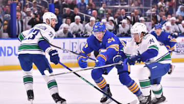 Nov 15, 2022; Buffalo, New York, USA; Buffalo Sabres center Dylan Cozens (24) skates the puck between Vancouver Canucks defenseman Oliver Ekman-Larsson (23) and defenseman Ethan Bear (74) in the second period at KeyBank Center. Mandatory Credit: Mark Konezny-USA TODAY Sports