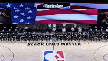 LAKE BUENA VISTA, FLORIDA - JULY 30: Members of the New Orleans Pelicans and Utah Jazz kneel before a Black Lives Matter logo before the start of their game at HP Field House at ESPN Wide World Of Sports Complex on July 30, 2020 in Reunion, Florida. NOTE TO USER: User expressly acknowledges and agrees that, by downloading and or using this photograph, User is consenting to the terms and conditions of the Getty Images License Agreement. (Photo by Pool/Getty Images)