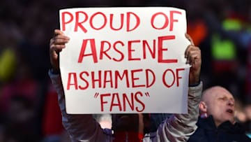 An Arsenal fan holds up a sign that reads 'Proud of Arsene, ashamed of fans', in a show of support for Arsenal's French manager Arsene Wenger, and a counter demonstration against those fans calling for change at the football club, during the English Premier League football match between Arsenal and Norwich at the Emirates Stadium in London on April 30, 2016. / AFP / BEN STANSALL / RESTRICTED TO EDITORIAL USE. No use with unauthorized audio, video, data, fixture lists, club/league logos or 'live' services. Online in-match use limited to 75 images, no video emulation. No use in betting, games or single club/league/player publications. / (Photo credit should read BEN STANSALL/AFP/Getty Images)