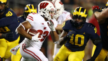 ANN ARBOR, MI - OCTOBER 13: Jonathan Taylor #23 of the Wisconsin Badgers tries to outrun the tackle of Devin Bush #10 of the Michigan Wolverines during the second half on October 13, 2018 at Michigan Stadium in Ann Arbor, Michigan. Michigan won the game 38-13. (Photo by Gregory Shamus/Getty Images)
