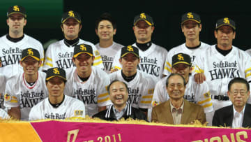 In a picture taken on November 20, 2011, Pacific League champions Softbank Hawks (first row L-R) manager Koji Akiyama, owner Masayoshi Son and chairman Sadaharu Oh smile with their players as they hold a large pennant to celebrate victory of the Japan Series professional baseball championship in Fukuoka, western Japan. The Hawks defeated Central League champion Chunichi Dragons 3-0 and clinched the Japan Series title 4-3. AFP PHOTO / JIJI PRESS (Photo by JIJI PRESS / JIJI PRESS / AFP) / Japan OUT (Photo credit should read JIJI PRESS/AFP via Getty Images)