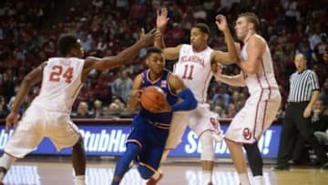 Feb 13, 2016; Norman, OK, USA; Kansas Jayhawks guard Frank Mason III (0) drives to the basket against Oklahoma Sooners guard Buddy Hield (24) and Oklahoma Sooners guard Isaiah Cousins (11) during the first half at Lloyd Noble Center. Mandatory Credit: Mark D. Smith-USA TODAY Sports