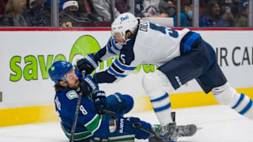 Dec 10, 2021; Vancouver, British Columbia, CAN; Winnipeg Jets defenseman Brenden Dillon (5) checks Vancouver Canucks forward Conor Garland (8) to the ice in the first period at Rogers Arena. Mandatory Credit: Bob Frid-USA TODAY Sports