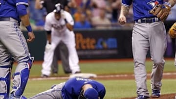 May 7, 2013; St. Petersburg, FL, USA; Toronto Blue Jays starting pitcher J.A. Happ (48) falls to the ground and grabs his head after he was hit by a line drive and Tampa Bay Rays center fielder Desmond Jennings (8) looks on after he hit the triple off him during the second inning at Tropicana Field Mandatory Credit: Kim Klement-USA TODAY Sports