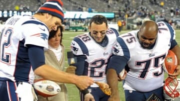 Nov 22, 2012; East Rutherford, NJ, USA; New England Patriots quarterback Tom Brady (12), safety Steve Gregory (28), and defensive tackle Vincent Wilfork (75) reach for a piece of a turkey while standing with NBC sports commentator Michele Tafoya after the game against the New York Jets on Thanksgiving at Metlife Stadium. The Patriots won the game 49-19. Mandatory Credit: Joe Camporeale-USA TODAY Sports