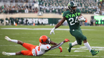 EAST LANSING, MICHIGAN - NOVEMBER 09: Elijah Collins #24 of the Michigan State Spartans gets around the tackle of Dele Harding #9 of the Illinois Fighting Illini for a first half touchdown at Spartan Stadium on November 09, 2019 in East Lansing, Michigan. (Photo by Gregory Shamus/Getty Images)
