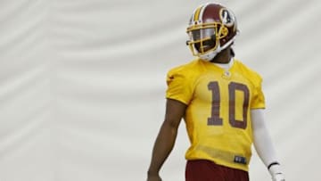 May 29, 2014; Ashburn, VA, USA; Washington Redskins quarterback Robert Griffin III (10) smiles while standing on the field during organized team activities at Redskins Park. Mandatory Credit: Geoff Burke-USA TODAY Sports