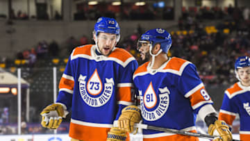 EDMONTON, CANADA - OCTOBER 29: Vincent Desharnais #73 (L and Darnell Nurse #25 of the Edmonton Oilers confer during a break in play against the Calgary Flames during the third period of the 2023 Tim Hortons NHL Heritage Classic at Commonwealth Stadium on October 29, 2023 in Edmonton, Alberta, Canada. The Oilers defeated the Flames 5-2. (Photo by Derek Leung/Getty Images)